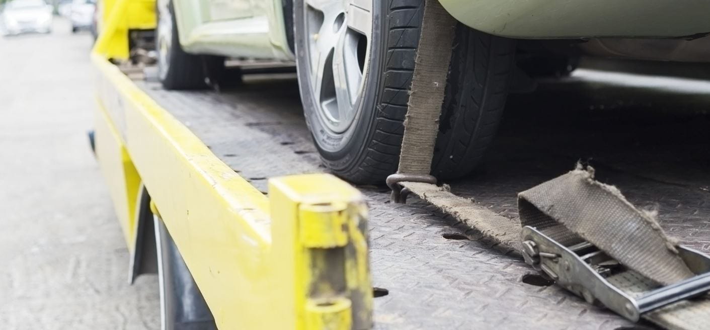 Car strapped down on a flatbed tow truck